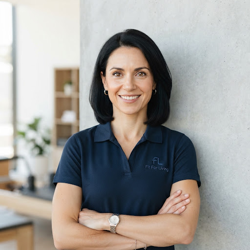 Professional headshot of Emma, female rehabilitation specialist and allied health personal trainer in navy polo shirt against light architectural concrete backdrop, friendly and capable.