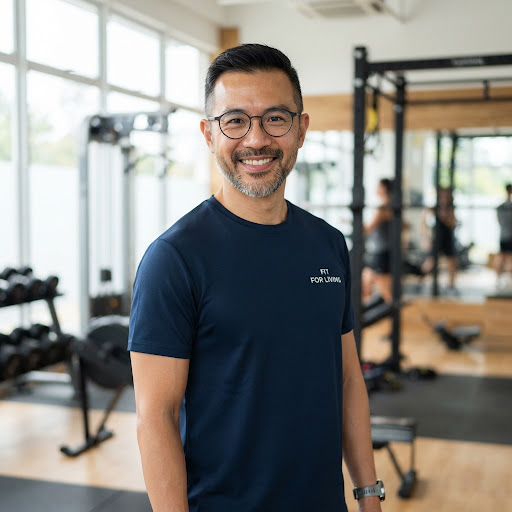 Headshot of experienced male coach with glasses in navy gym apparel in daylight gym studio setting.